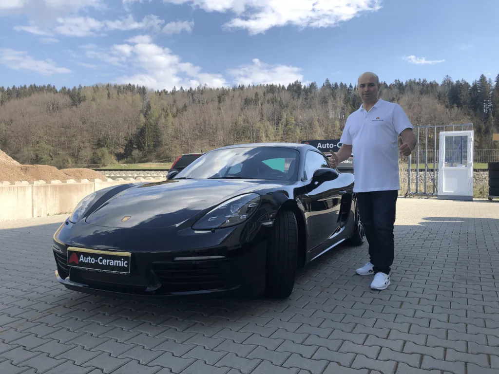 Sergej Gossen, Inhaber von Auto-Ceramic.de, neben einem schwarzen Porsche Cayman nach Keramikbeschichtung